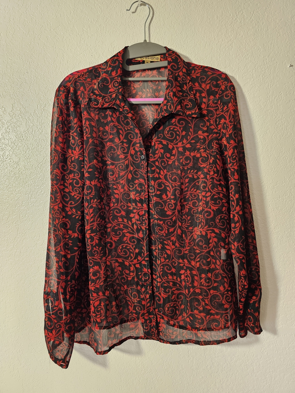 Notations blouse features a sheer black fabric with a vibrant red vine pattern